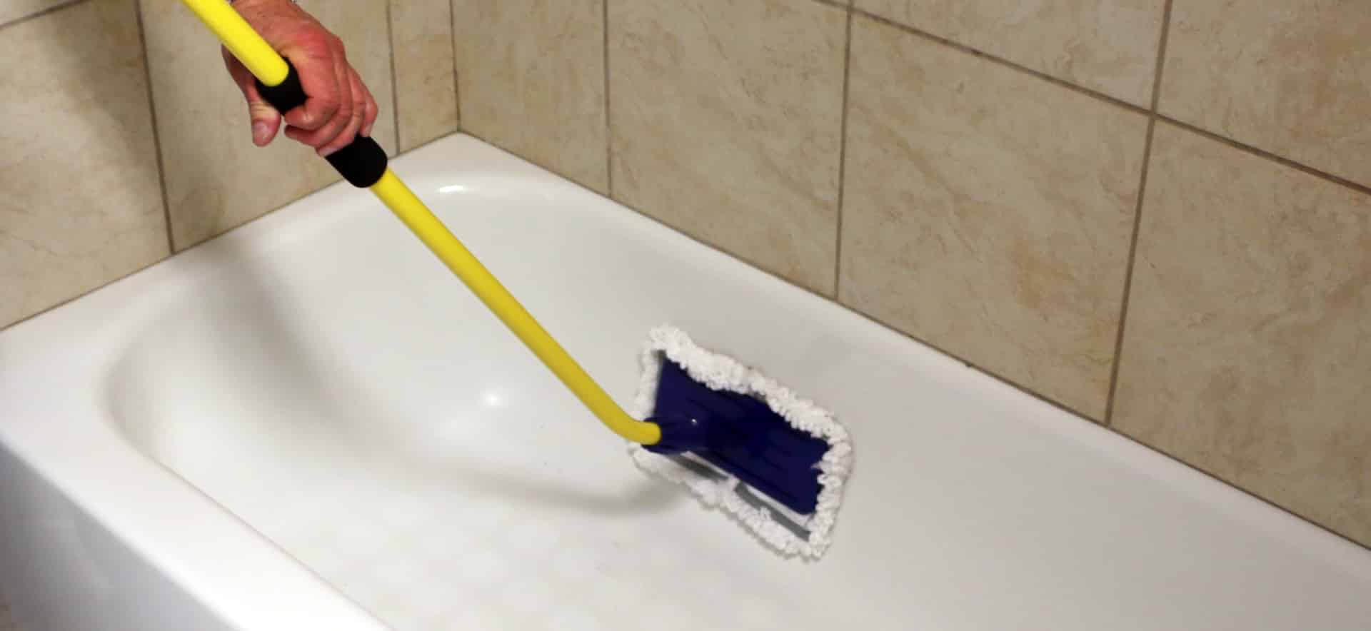 A person uses a Simple Scrub to clean the side of a bath tub.