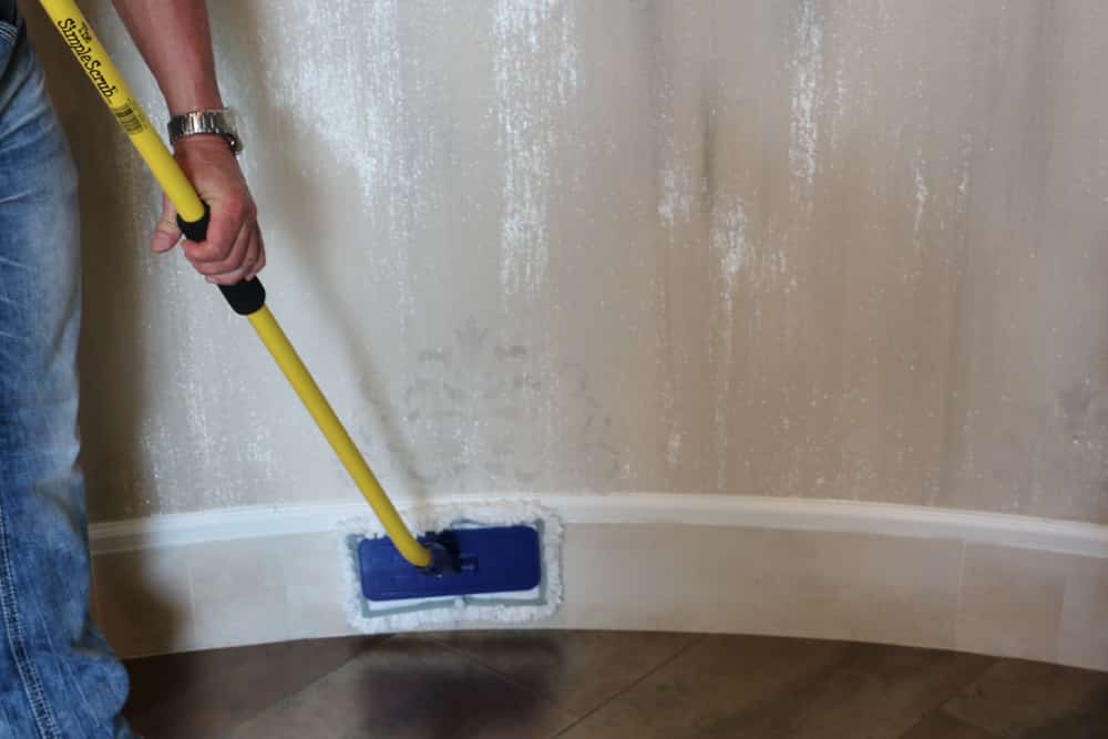 Man cleaning floorboards with The Simple Scrub Original.