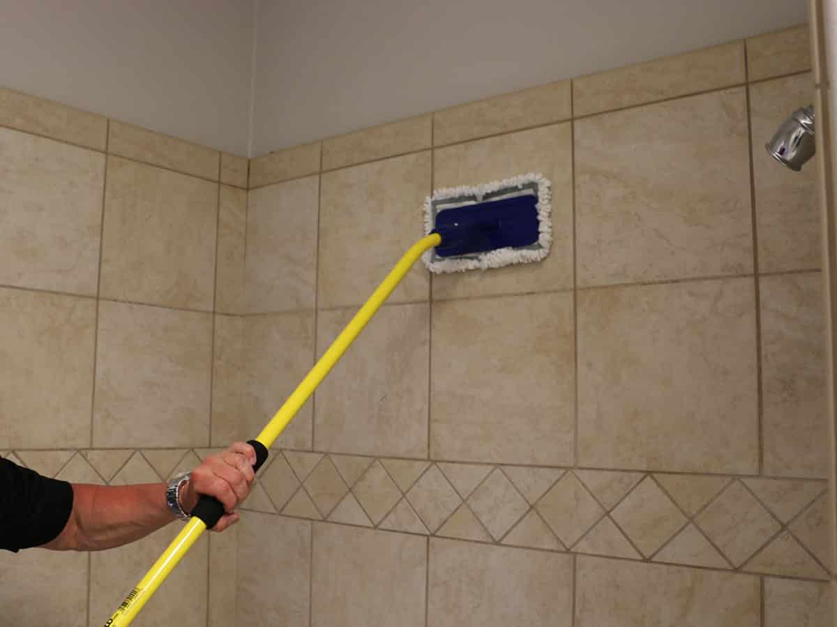 Man cleans shower tiles with The Simple Scrub Original.