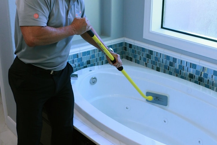 Man cleaning bathtub with The Simple Scrub Original.
