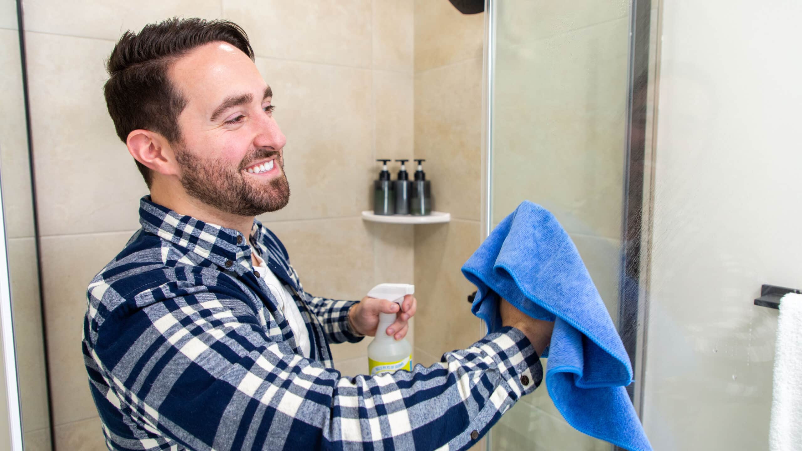 A man cleans his bathroom with Simple Scrub spray, following the ideal routine for cleaning the bathroom.